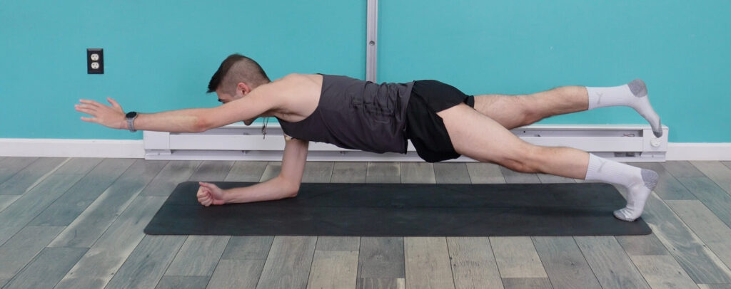 In a forearm plank doing a superman with his right forearm on the ground left arm extended and left toes on the ground right foot lifted